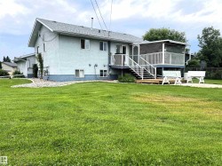 Expansive green space featuring a two-story residence with a screened-in upper deck, lower wood-finish landing, and an outdoor patio - 