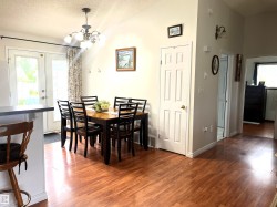 Dining area featuring a wood-finish floor, white walls, and a multi-light chandelier - 