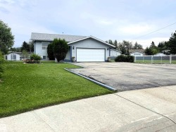 Light blue stucco exterior with a gray shingle roof, featuring an attached two-car garage with a white door - 