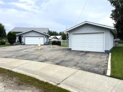 Property featuring a detached garage with a white panel door, stucco exterior, and asphalt driveway - 