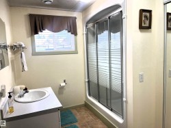 Bathroom featuring an enclosed shower with sliding frosted glass doors, a single vanity with an integrated sink, and an overhead window with horizontal blinds - 