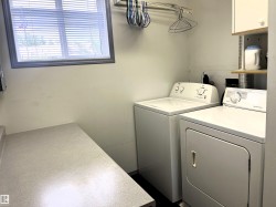 Laundry area featuring a window with blinds, a built-in countertop, and an overhead clothes hanging rod - 