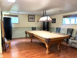 Recreation room featuring wood-finish flooring, light green wainscoting, and a drop ceiling - 