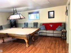 Recreation space featuring wood-finish flooring, a suspended light fixture, and wainscoting - 