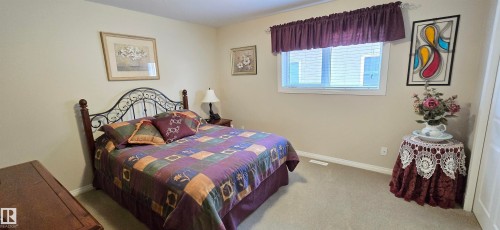 Carpeted room featuring a white-framed window with blinds, baseboard trim, and light neutral wall paint - 4221 46 Street, Vegreville, AB 