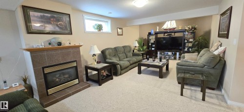 Living area featuring a gas fireplace with a tiled surround and wood mantel - 4221 46 Street, Vegreville, AB 