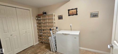 Tile flooring with a decorative area rug, bi-fold closet doors, and light-toned walls - 4221 46 Street, Vegreville, AB 