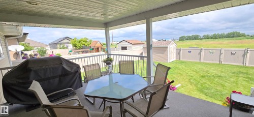Covered outdoor patio with a textured floor and white railing - 4221 46 Street, Vegreville, AB 