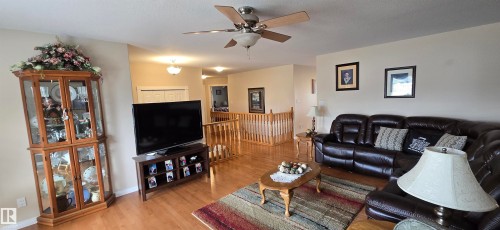 Open-concept living area featuring wood-finish flooring, a ceiling fan with integrated lighting, and a light-toned neutral wall color - 4221 46 Street, Vegreville, AB 