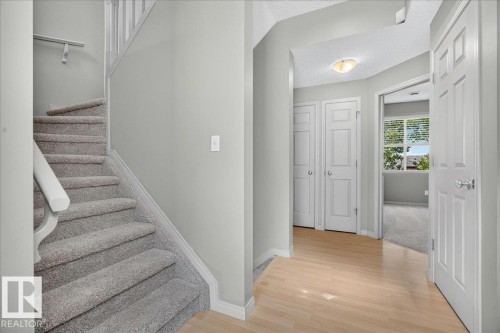 Light wood-finish flooring extending through the hallway, complemented by light gray wall paint and white trim - 20 4821 Terwillegar Common, Edmonton, AB 