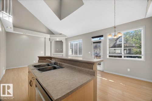 Kitchen island with a double stainless steel sink and light-toned countertop - 20 4821 Terwillegar Common, Edmonton, AB 