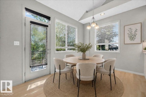 Dining area featuring a contemporary chandelier, multiple windows with blinds, a glass-paneled door with a transom window, wood-finish flooring, and light gray walls - 20 4821 Terwillegar Common, Edmonton, AB 