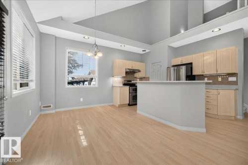 Open-concept kitchen and dining area featuring light wood-finish flooring, light grey walls, and vaulted ceilings - 20 4821 Terwillegar Common, Edmonton, AB 