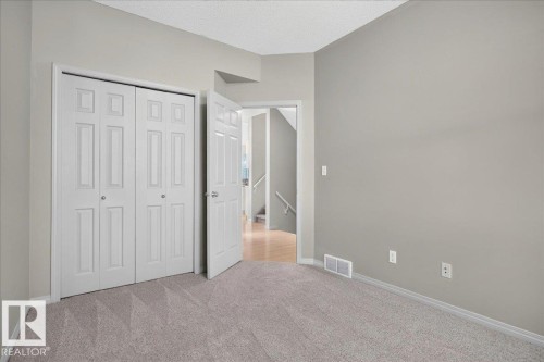 Spacious room featuring neutral carpeting, light gray wall paint, and white bi-fold closet doors - 20 4821 Terwillegar Common, Edmonton, AB 