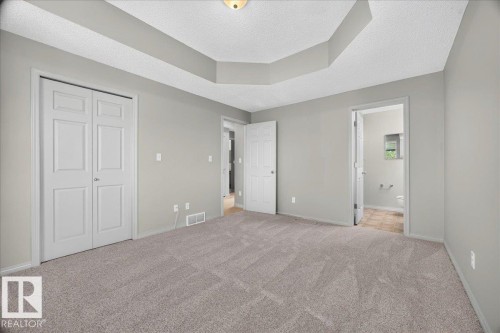Carpeted room featuring a tray ceiling, light gray wall paint, and white trim - 20 4821 Terwillegar Common, Edmonton, AB 