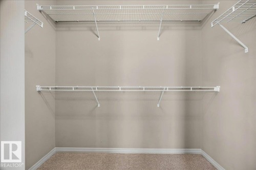 Walk-in closet featuring light beige walls and light brown carpet flooring - 20 4821 Terwillegar Common, Edmonton, AB 