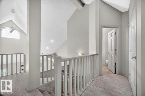 Loft area featuring vaulted ceilings, a ceiling fan with light fixture, and a spacious arched window - 20 4821 Terwillegar Common, Edmonton, AB 