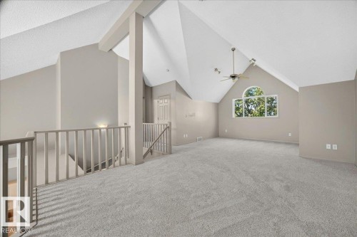 Spacious upper-level room featuring high vaulted ceilings, light gray carpet, and a prominent arched window - 20 4821 Terwillegar Common, Edmonton, AB 