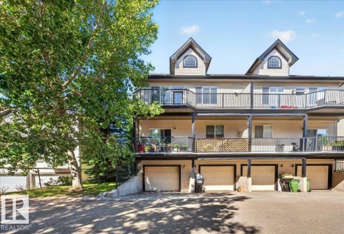 Multi-level townhome featuring dormer windows, individual balconies with black railings, and ground-level garage access - 20 4821 Terwillegar Common, Edmonton, AB 