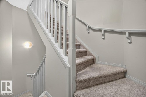 Carpeted staircase featuring white painted banisters and handrails - 20 4821 Terwillegar Common, Edmonton, AB 