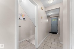 Foyer featuring tile flooring, a light gray entry door with an arched window, and overhead lighting - 