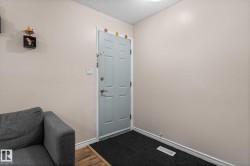 Entryway featuring a paneled door with brushed nickel hardware, light-toned wall finishes, and wood-finish flooring - 