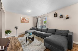 Light-toned walls with contrasting baseboards, wood-finish flooring, and a large window with exterior siding visible - 