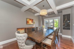 Dining space featuring a coffered ceiling with recessed lighting, wood-finish flooring, and a large window - 