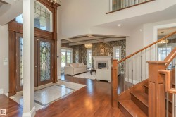 Grand entryway featuring double-height ceilings, wood-finish flooring, and a decorative staircase with metal balusters - 