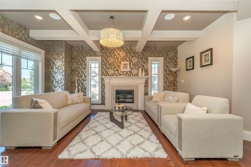 Living area featuring a coffered ceiling, hardwood flooring, and an ornate fireplace with a white mantel - 3503 Watson Point(E), Edmonton, AB 