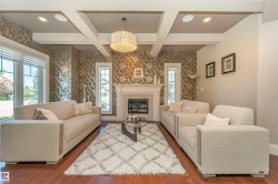 Living area featuring a coffered ceiling, hardwood flooring, and an ornate fireplace with a white mantel - 