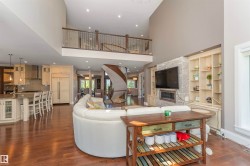 Two-story living area featuring hardwood flooring, a stone-accented fireplace surround, and built-in shelving - 