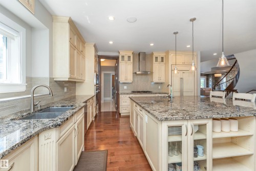 Spacious kitchen featuring an expansive island with seating, light-toned cabinetry, granite countertops, and wood-finish flooring - 3503 Watson Point(E), Edmonton, AB 