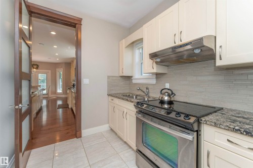 Kitchen featuring stainless steel appliances, granite countertops, cream-colored cabinetry, a horizontal tile backsplash, and light-toned floor tiling - 3503 Watson Point(E), Edmonton, AB 