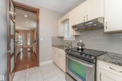 Kitchen featuring stainless steel appliances, granite countertops, cream-colored cabinetry, a horizontal tile backsplash, and light-toned floor tiling - 