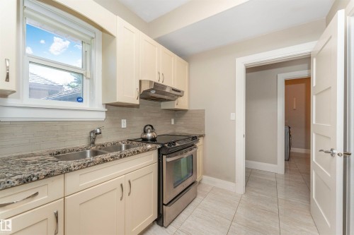 Kitchen featuring light cabinetry with brushed nickel hardware, a stainless steel double basin sink, and a stainless steel oven range with an overhead vent - 3503 Watson Point(E), Edmonton, AB 