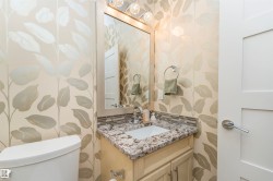 Powder room featuring a single vanity with a granite countertop, undermount sink, and mosaic tile backsplash - 