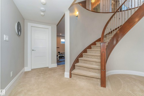 Curved wooden staircase with metal balusters and carpeted treads - 3503 Watson Point(E), Edmonton, AB 