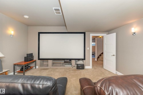 Entertainment room featuring a large projection screen, wall-mounted sconce lighting, and plush carpet flooring - 3503 Watson Point(E), Edmonton, AB 