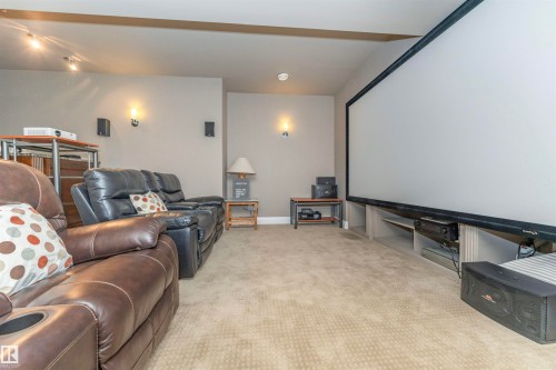 Dedicated media room featuring a large projection screen, integrated entertainment shelving, track lighting, and wall sconces - 3503 Watson Point(E), Edmonton, AB 