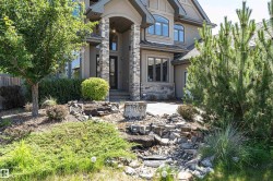 Stucco and stone exterior featuring an arched portico entryway, multiple window styles, and a gabled roofline - 