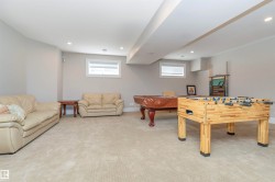 Spacious recreational area featuring light-colored carpeting, neutral painted walls, and recessed lighting - 