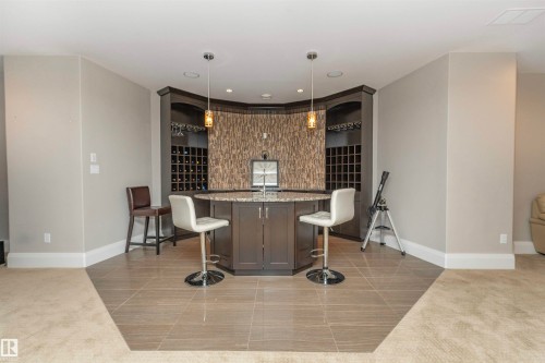 Custom built-in wet bar featuring dark wood cabinetry, integrated wine storage, and a textured backsplash - 3503 Watson Point(E), Edmonton, AB 