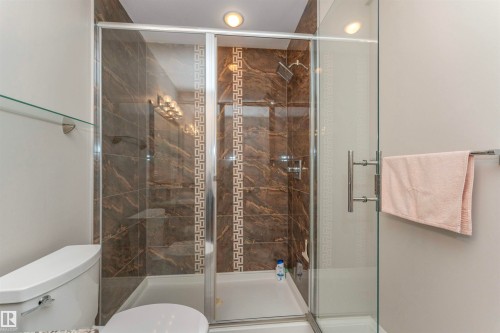 Glass-enclosed shower with brown marbled tile surround and decorative tile accent - 3503 Watson Point(E), Edmonton, AB 
