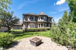 Exterior stucco residence featuring a multi-level deck, ground-level stone patio, and a domed turret with multiple windows - 