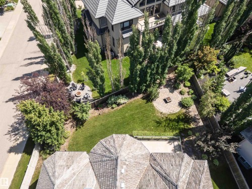 Expansive backyard featuring a circular paver patio with a built-in fire pit, a secondary paver patio, mature trees providing natural screening, and a manicured lawn - 3503 Watson Point(E), Edmonton, AB 