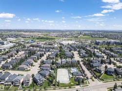 Expansive aerial depicting a residential neighborhood with numerous detached homes, street infrastructure, and mature trees - 