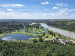 Expansive riverfront property featuring a golf course with multiple water hazards, mature tree lines, a significant river, and a dedicated parking area with a clubhouse structure - 