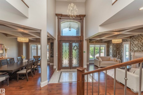 Grand foyer featuring a double-height ceiling, dark wood-finish double entry doors with decorative glass inserts, and a tiled entryway - 3503 Watson Point(E), Edmonton, AB 