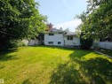 Expansive backyard featuring a manicured lawn, mature shade trees, and a white privacy fence - 5012 143 Street, Edmonton, AB 